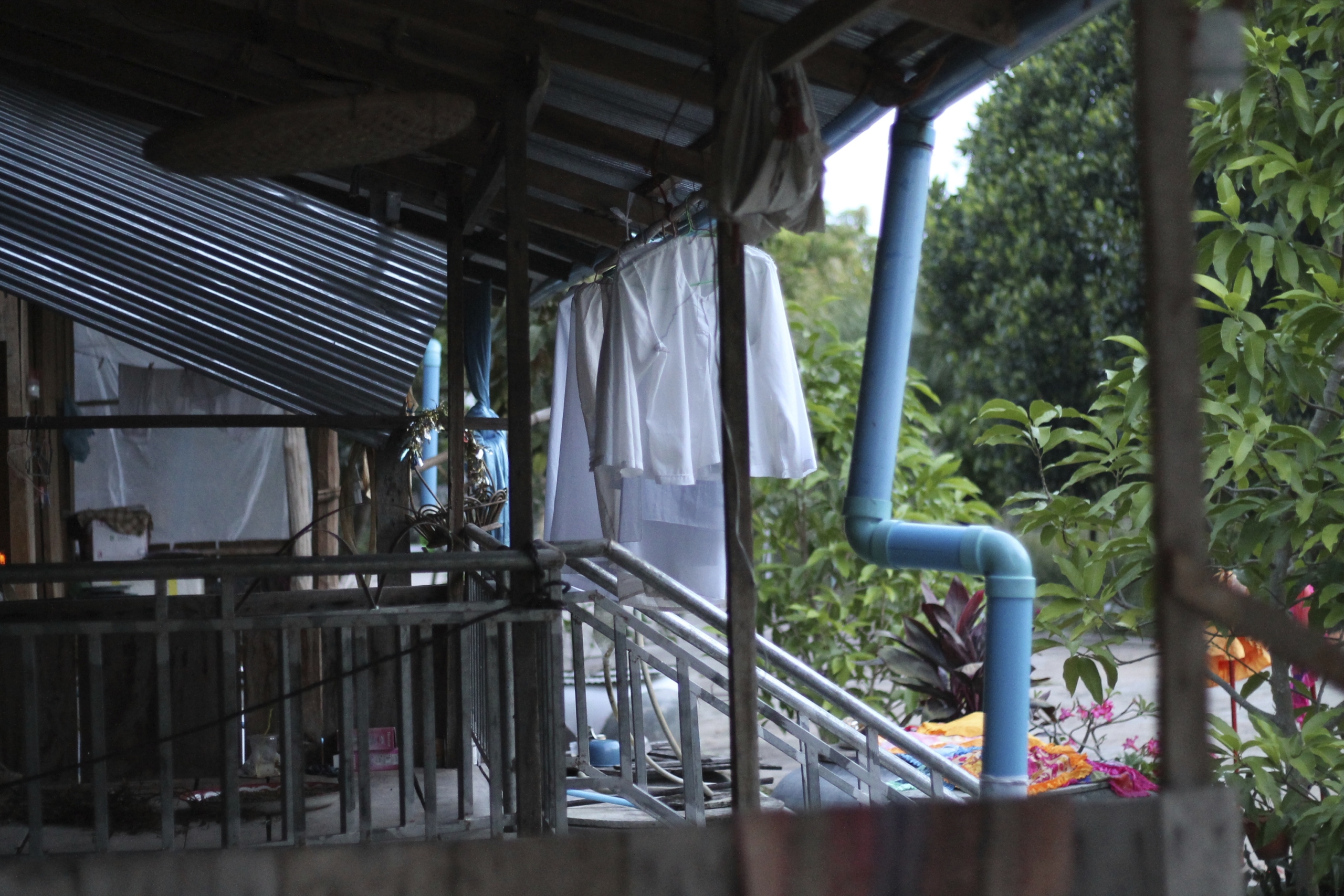 Living quarters of donji at the Buddhist Center. Corrugated metal awning over a small deck with metal railings. You can see these female renunciants’ white robes drying after a wash.