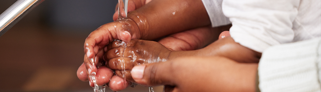 baby and parent's hands under running water
